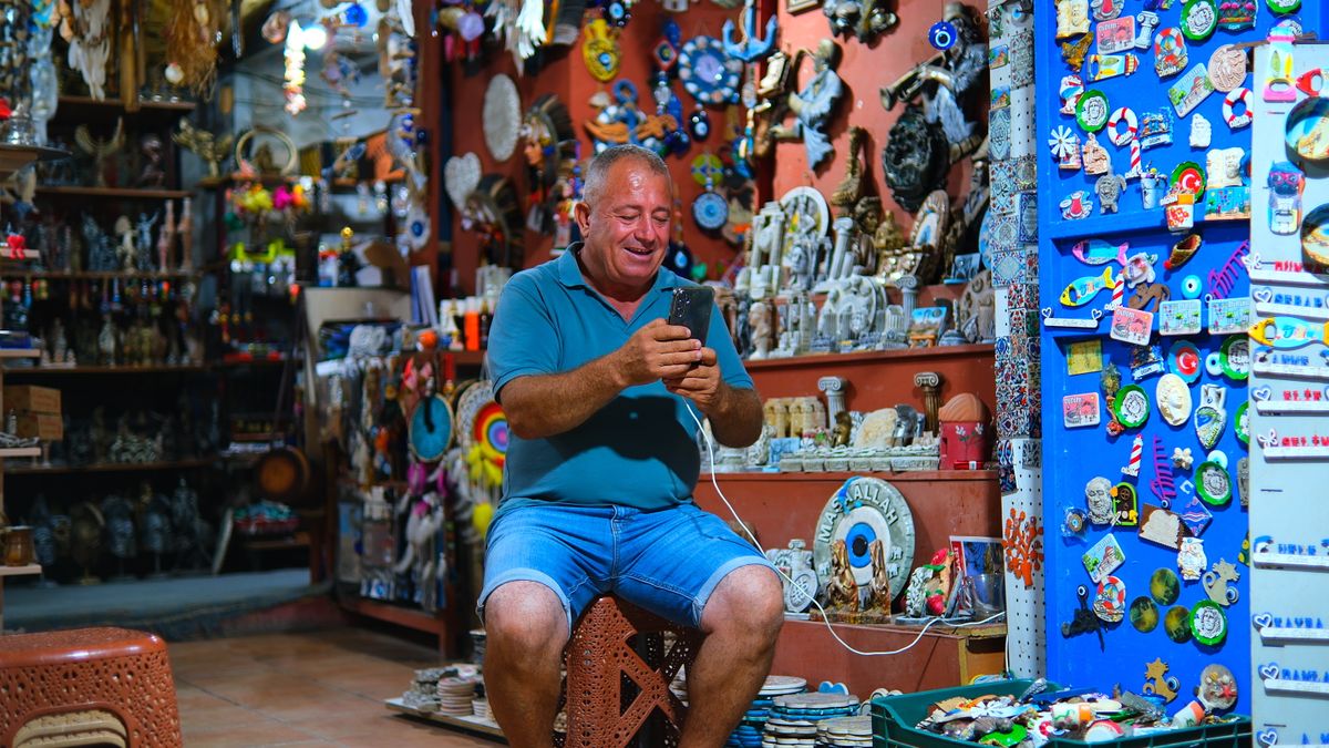 Un comerciante sentado en su tienda mirando el teléfono