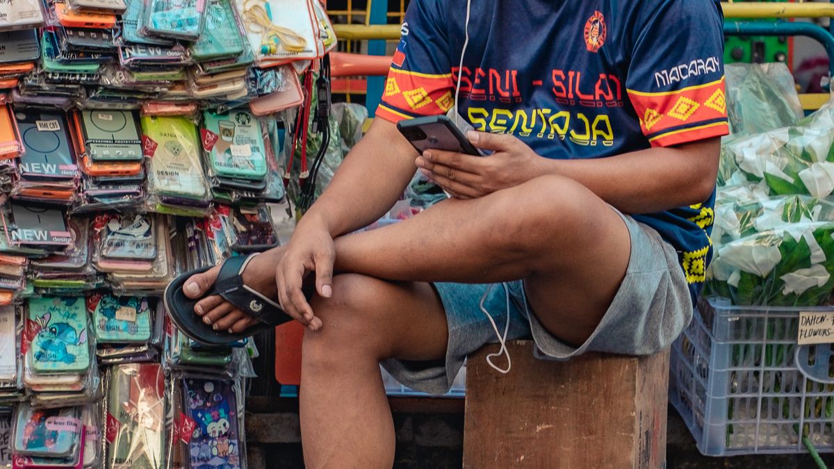 A shopkeeper at the counter looking at a phone